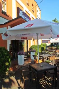 un patio con mesas, sillas y una sombrilla en Hotel Bursztyn, en Kalisz