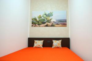 a bedroom with a bed with an orange blanket and a cactus at Villetta Sofia in Marina di Pescoluse