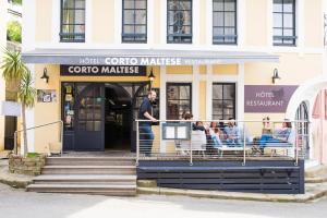 a group of people sitting outside of a coffee shop at Hôtel Restaurant Corto Maltese in Le Palais