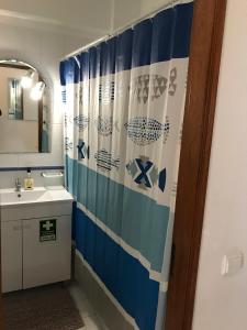 a bathroom with a sink and a shower curtain at Edificio Caravela C in Armação de Pêra