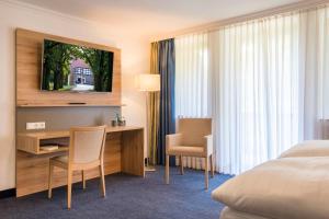 Pokój hotelowy z łóżkiem, biurkiem i krzesłami w obiekcie IDINGSHOF Hotel & Restaurant w mieście Bramsche