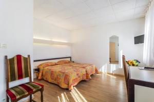 ein Schlafzimmer mit einem Bett und einem Stuhl in einem Zimmer in der Unterkunft Logis Hotel Restaurant Remotel in Knutange
