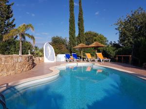 a swimming pool with chairs and umbrellas in a yard at Quinta Teresinha in Silves