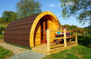 dwoje ludzi siedzących w małej drewnianej szopie w obiekcie Glendalough Glamping - Adults Only w mieście Laragh