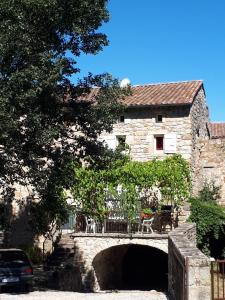 a stone building with a bridge and a car in front at Gîtes Mas de la Musardière in Les Assions