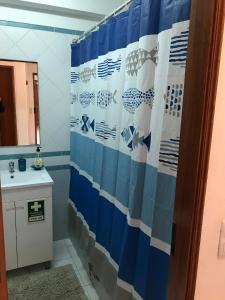 uma casa de banho com uma cortina de chuveiro azul e branco em Edificio Fragata A em Armação de Pêra