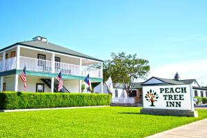 ein Haus mit einem Schild, das Pfirsichbaum-Gasthaus liest in der Unterkunft Peach Tree Inn & Suites in Fredericksburg