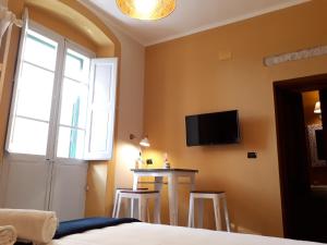 a bedroom with a bed and a table and a tv on the wall at Sofia Family Suites in Carloforte