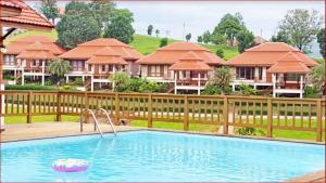 a swimming pool in front of some houses at Thongsathit Hill Resort Khao Yai in Nong Nam Daeng