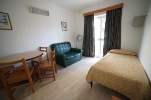 a living room with a couch and a table and a chair at Cardor Holiday Complex in St Paul's Bay