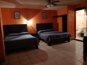 two beds in a room with orange walls at Hotel del Conde in Guanajuato