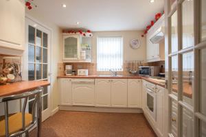 a large kitchen with white cabinets and a sink at Oil Mill Lane Holiday Cottage in Berwick-Upon-Tweed