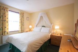 a bedroom with a white bed with a canopy at Oil Mill Lane Holiday Cottage in Berwick-Upon-Tweed