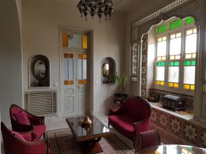 a living room with red chairs and a table and windows at Maison d'Hôtes Dar Ennassim in La Marsa