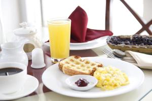 a table with a plate of breakfast food and a glass of orange juice at Hotel Flor de Liz in Guayaquil