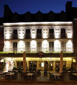 een verlicht gebouw met tafels en stoelen ervoor bij Cit'Hotel le Challonge in Dinan