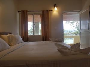 a bedroom with a large white bed with windows at Dew Drops Farm Resorts in Munnar