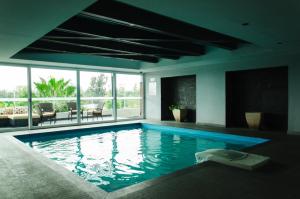 a large swimming pool with blue water in a room at Casa Inn Business Hotel Celaya in Celaya