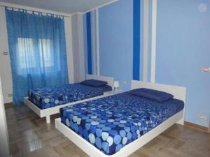 two beds sitting in a bedroom with blue curtains at Le Stagioni in Spezzano della Sila