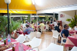 a group of people sitting at tables in a restaurant at Camping Torre Castiglione in Torre Lapillo