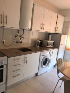 a kitchen with white cabinets and a washing machine at Edificio Caique C in Armação de Pêra