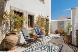 a patio with chairs and a table and potted plants at Villa Anastasia in Líndos