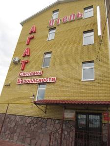 a yellow brick building with a red sign on it at Hotel Agat in Tyumen