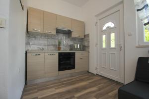 a kitchen with wooden cabinets and a window and a door at Apartment Afrodita in Kaštela