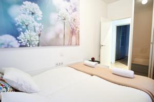 1 dormitorio con 1 cama blanca y una pintura en la pared en Bordador Bicycle City Center by Valcambre, en Sevilla