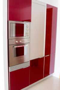 a red and white kitchen with a stove and microwave at Mountain and Sea in Ribeira Grande