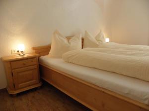 Schlafzimmer mit einem Bett mit weißer Bettwäsche und einem Nachttisch in der Unterkunft Waldner's Ferienwohnung in Hermagor