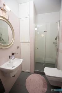 a white bathroom with a sink and a shower at Warsaw Concierge Vistula Apartment in Warsaw