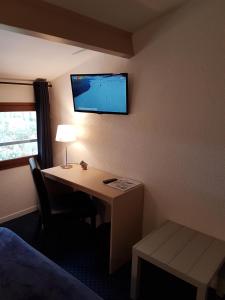 Habitación de hotel con escritorio y TV en la pared en Les Jardins de L'Ocean en Biscarrosse-Plage