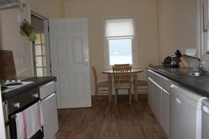 a kitchen with a sink and a table in it at Carrick Farm Lochside Appartment (GF) in Lochgoilhead