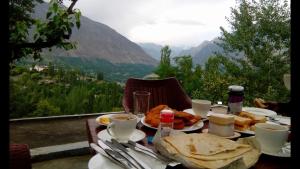 a table with plates of food and a view of a mountain at Baltit Heritage Inn in Hunza Valley