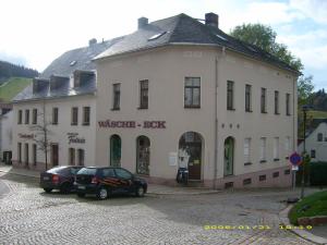 un bâtiment avec deux voitures garées devant lui dans l'établissement Ferienwohnung Alte Apotheke, à Eibenstock