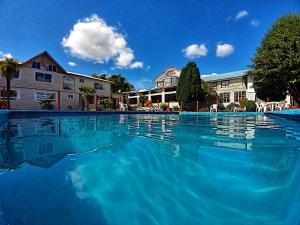 una gran piscina de agua azul frente a las casas en Hotel Casa de la Oma, en Frutillar