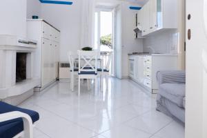 ソレントにある"White Mermaid" - SORRENTO DOWNTOWN SEA VIEW APARTMENTの白いキッチン(テーブル、椅子付)