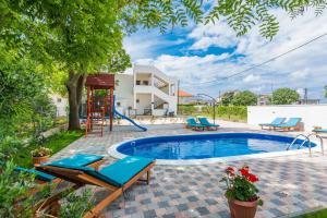 a swimming pool in a yard with chairs and a house at Apartments Marina in Bibinje