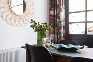 a dining room table with a vase of flowers and a mirror at HOTELdeBEAUTEL in Vlissingen