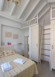 a white bedroom with a bed and a ladder at Blue Wave Astradeni House in Symi