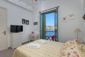 a bedroom with a bed and a tv and a window at Blue Wave Astradeni House in Symi