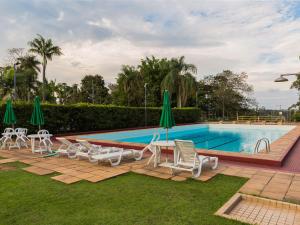 a swimming pool with chairs and a table and umbrellas at Hotel Escola Bela Vista in Volta Redonda