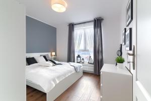 a white bedroom with a white bed and a window at Bastion Wałowa in Gdańsk