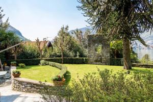 un jardín con una pared de piedra y un patio de césped en Stylish JOIVY Flat with Garden, en Pognana Lario