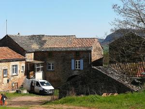 een auto geparkeerd voor een bakstenen huis bij Gîte de Grailhes in Aguessac