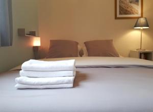 a bed with towels stacked on top of it at Le Coquet in Saint-Omer