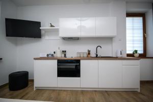a white kitchen with white cabinets and a sink at Apartamenty AP 1 in Częstochowa