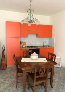 eine Küche mit orangefarbenen Schränken und einem Holztisch mit Stühlen in der Unterkunft Appartamenti LaConia Cannigione in Cannigione