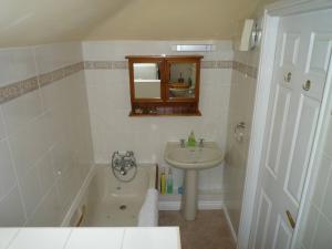 La salle de bains est pourvue d'un lavabo et d'une baignoire. dans l'établissement Rose Cottage, Meathop Grange, à Grange-over-Sands